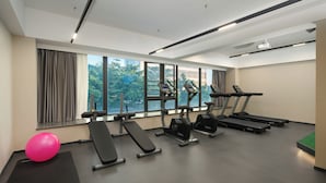 Un gimnasio moderno con cintas de correr, elípticas y una banca.