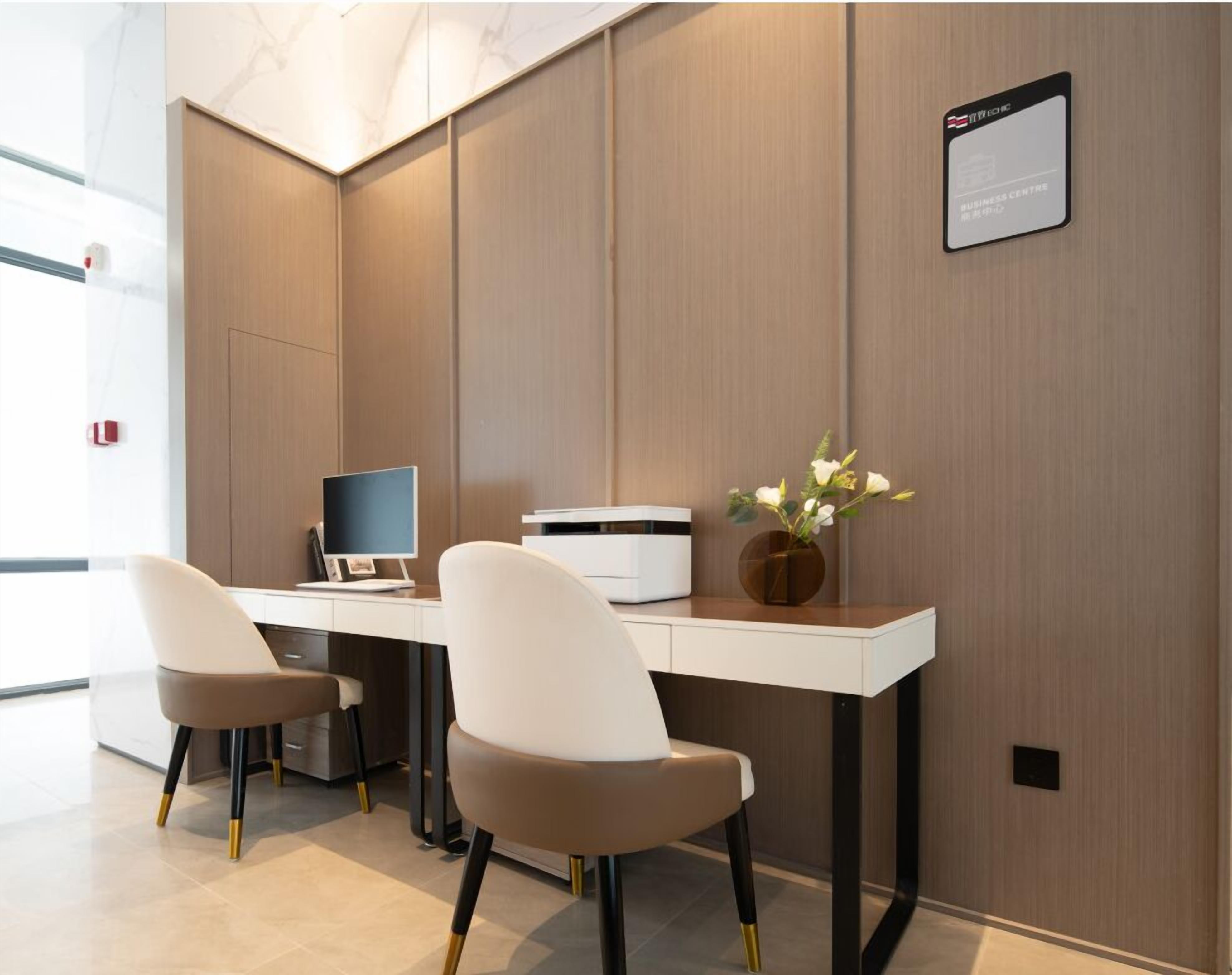 Ein moderner Arbeitsraum mit einem Schreibtisch, zwei Stühlen, einem Computerbildschirm, einem Drucker und einer Vase mit Blumen.