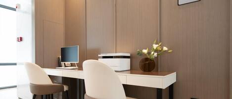 Ein moderner Arbeitsraum mit einem Schreibtisch, zwei Stühlen, einem Computerbildschirm, einem Drucker und einer Vase mit Blumen.