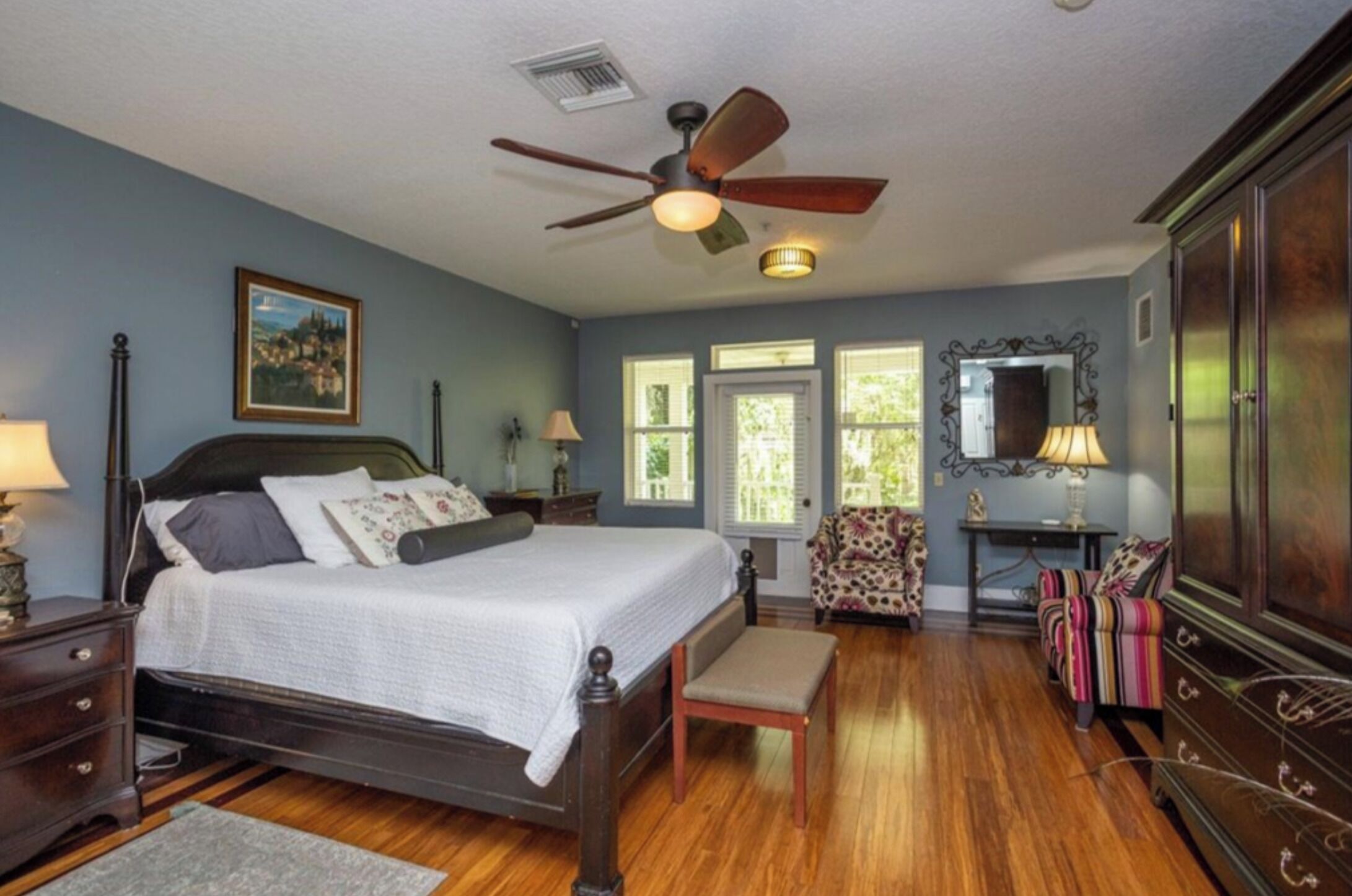 A bedroom with a bed, a chair, a desk, and a wardrobe.
