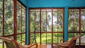 Una habitación con ventanas amplias, muebles de madera y un trípode.