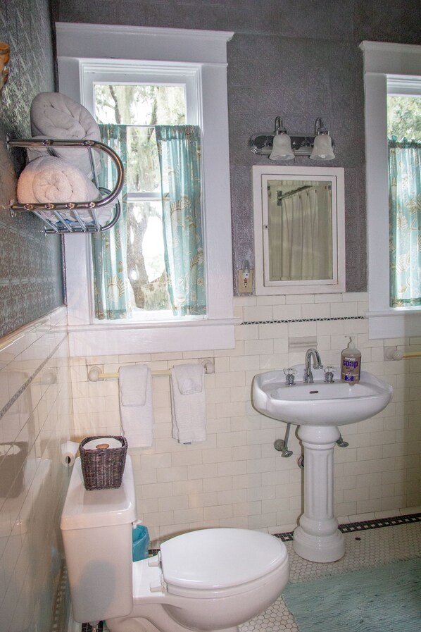 Un baño con inodoro, lavabo y ventana con cortinas.