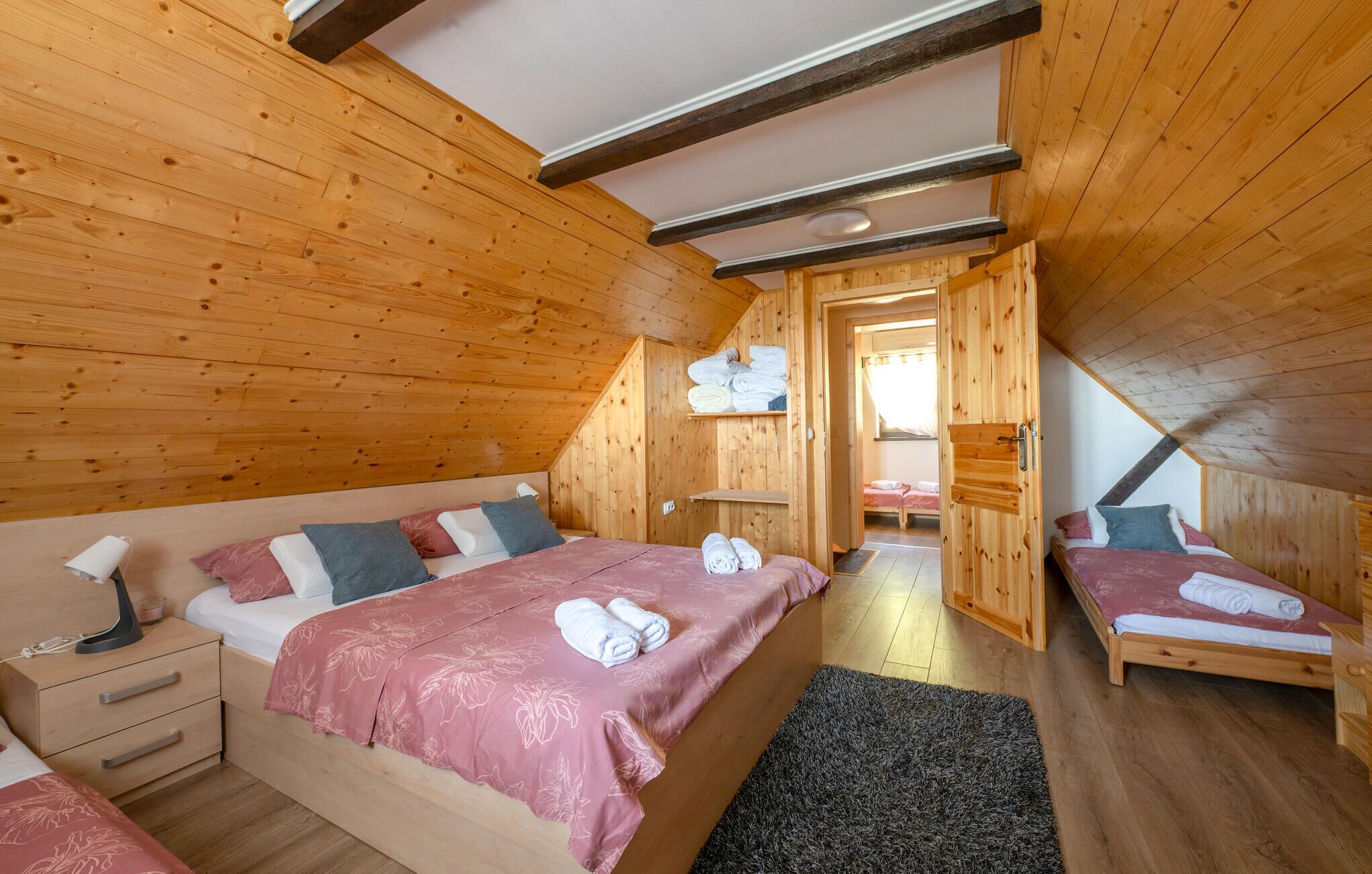 A wooden cabin bedroom with a large bed, a smaller bed, and a walk-in closet.