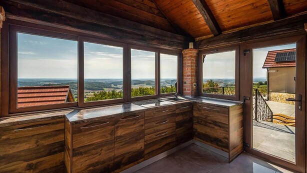 A kitchen with large windows offering a view of the countryside. - Luxurious home in Kamesnica with sauna (Kamesnica)