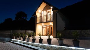 A two-story house with a balcony, potted plants in front, and a stone wall. - Luxurious home in Kamesnica with sauna (Kamesnica)