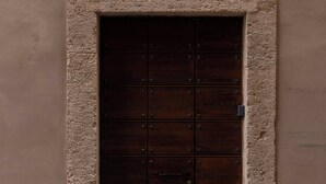A dark wooden door with metal reinforcements, a window with metal bars, and a building number sign. - 2 Luxury Suites on the Same Floor - 1 min from Piazza Navona (Roma)