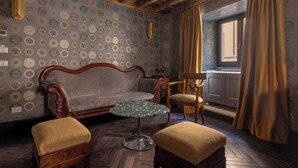 A room with a patterned wallpaper, a wooden ceiling, a sofa, two armchairs, a small table, and a window with curtains. - 2 Luxury Suites on the Same Floor - 1 min from Piazza Navona (Roma)