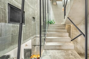 A modern staircase with glass railings and concrete walls, leading to an upper floor. - Huyan Museum BnB - Concrete Design (Liuqiu)