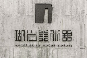 A sign with the text "MUSÉE DE LA ROCHE CORAIL" on a concrete wall. - Huyan Museum BnB - Concrete Design (Liuqiu)