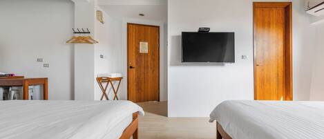 A hotel room with two beds, a TV, wooden doors, and a small desk with a chair.