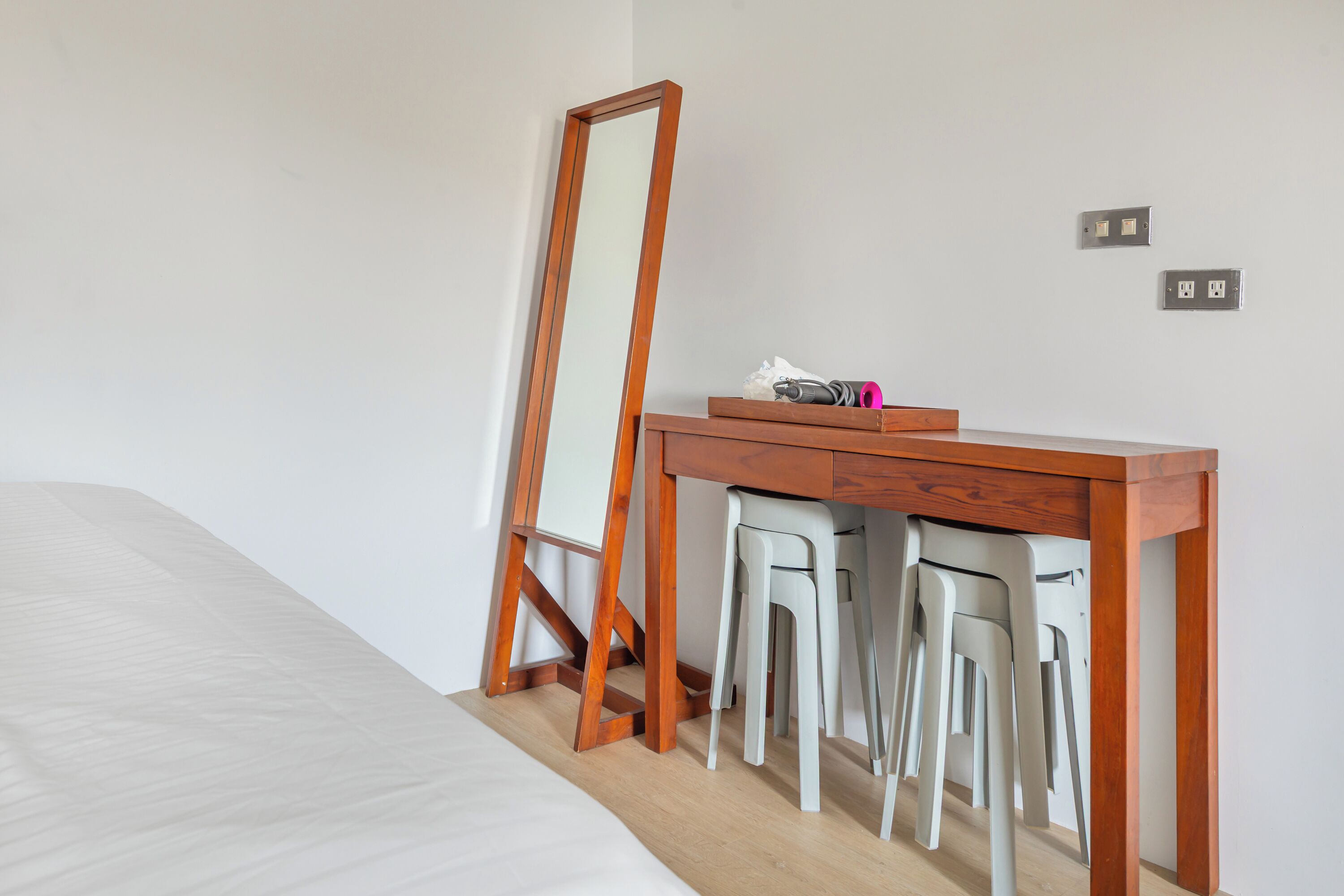 Ein Schlafzimmer mit einem Holztisch, zwei weißen Stühlen, einem Spiegel und einem Bett.