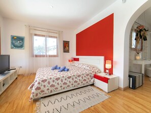 Relax in this serene bedroom with a large bed, flat-screen TV, and a decorative rug.