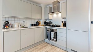 A modern kitchen with white cabinetry, a built-in oven, and a stainless steel range hood.