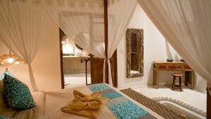 A bedroom with a bed, a bedside table, a mirror, and a view of the bathroom.