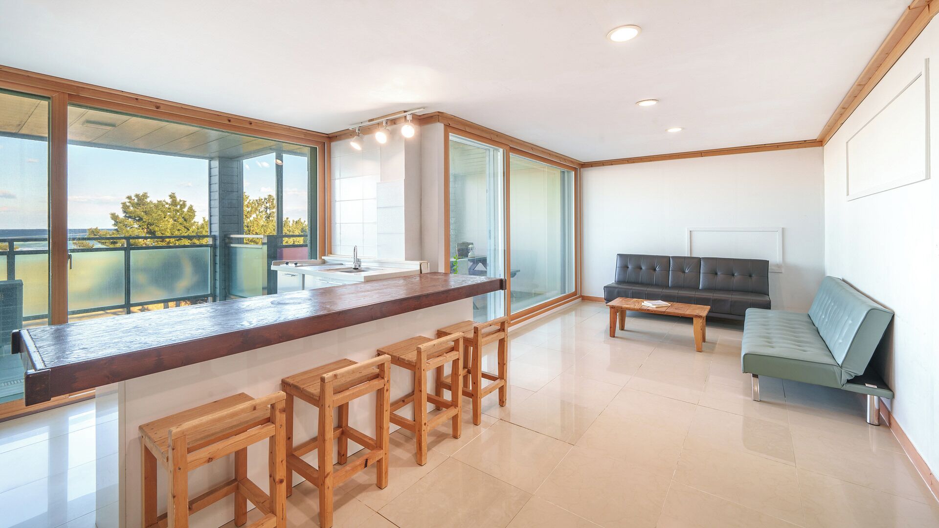 Una cocina moderna con un ventanal grande, una barra y una zona de estar con sofá y sillones.