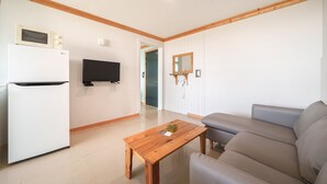 A modern living room with a flat-screen TV, a white refrigerator, a wooden coffee table, and a grey sofa. - Yangyang Bono Pet-friendly Pension (Yangyang)
