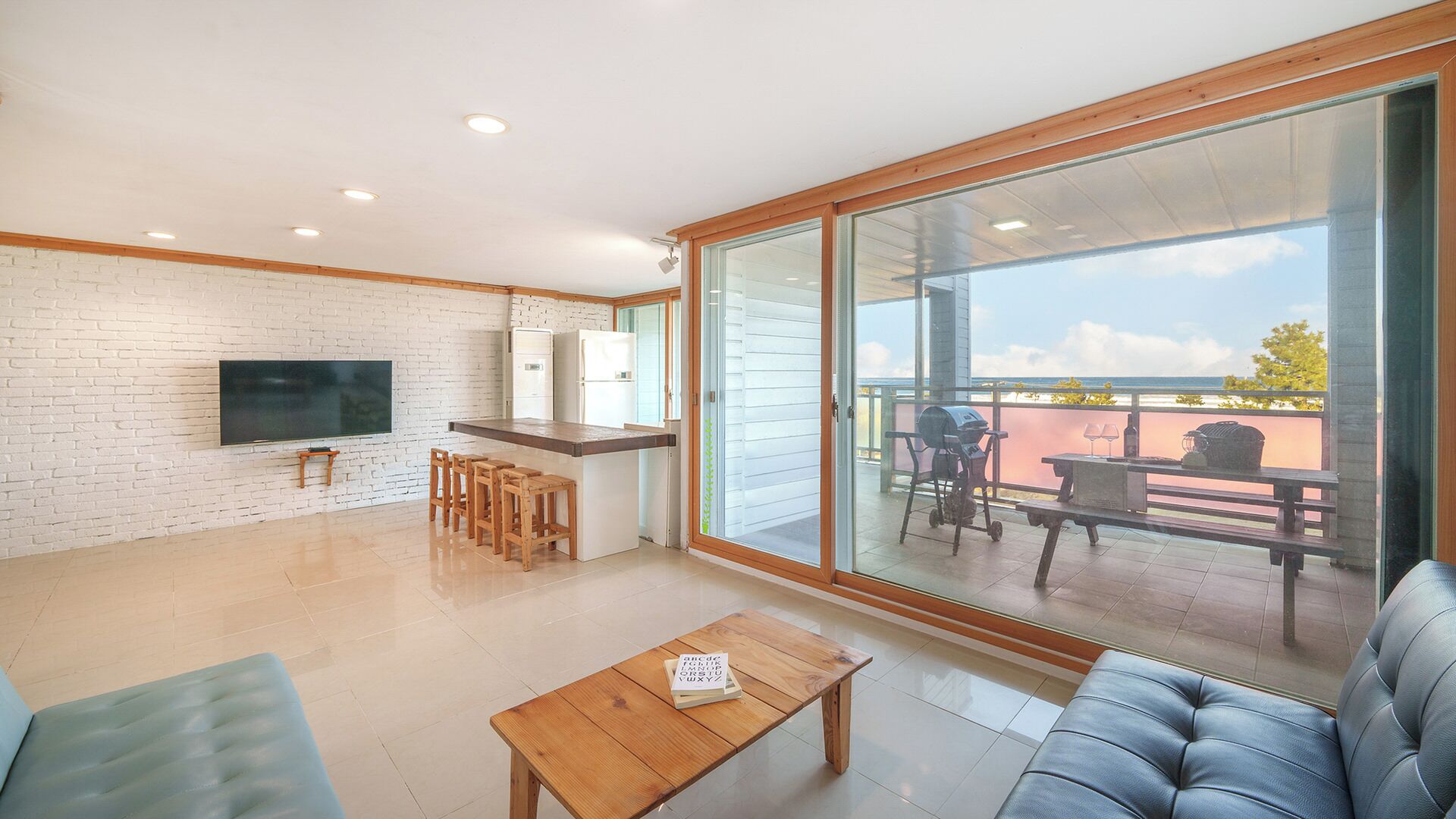 A modern living space with a kitchen, a dining area, and a balcony with a view.