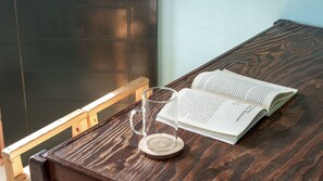 A wooden table with an open book and a clear glass mug. - Yangyang Bono Pet-friendly Pension (Yangyang)