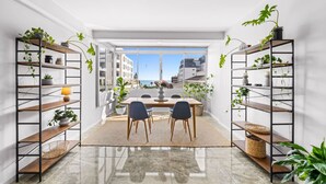 Un interior moderno con zona de comedor, dos sillas, una mesa y estanterías con plantas.