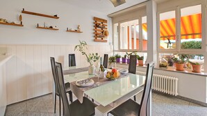 A dining area with a glass table, chairs, and a variety of potted plants. - Casa Tecitt with Shared Pool in Val Resa, Brione Sopra Minusio, Switzerland (Brione Sopra Minusio)
