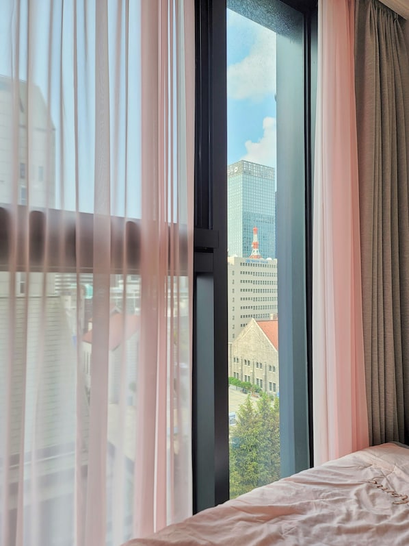 Ein Hotelzimmer mit großem Fenster, Vorhängen und einem Bett.