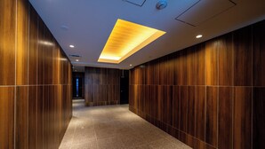 Um corredor com paredes de painel de madeira e chão de azulejos, que leva a uma porta escura.