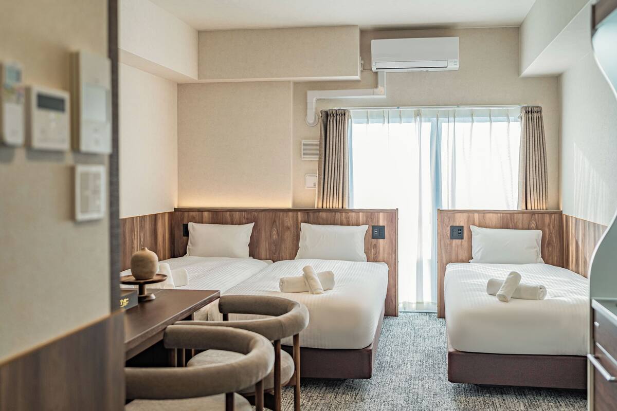 Habitación de hotel con dos camas, un escritorio y una silla.