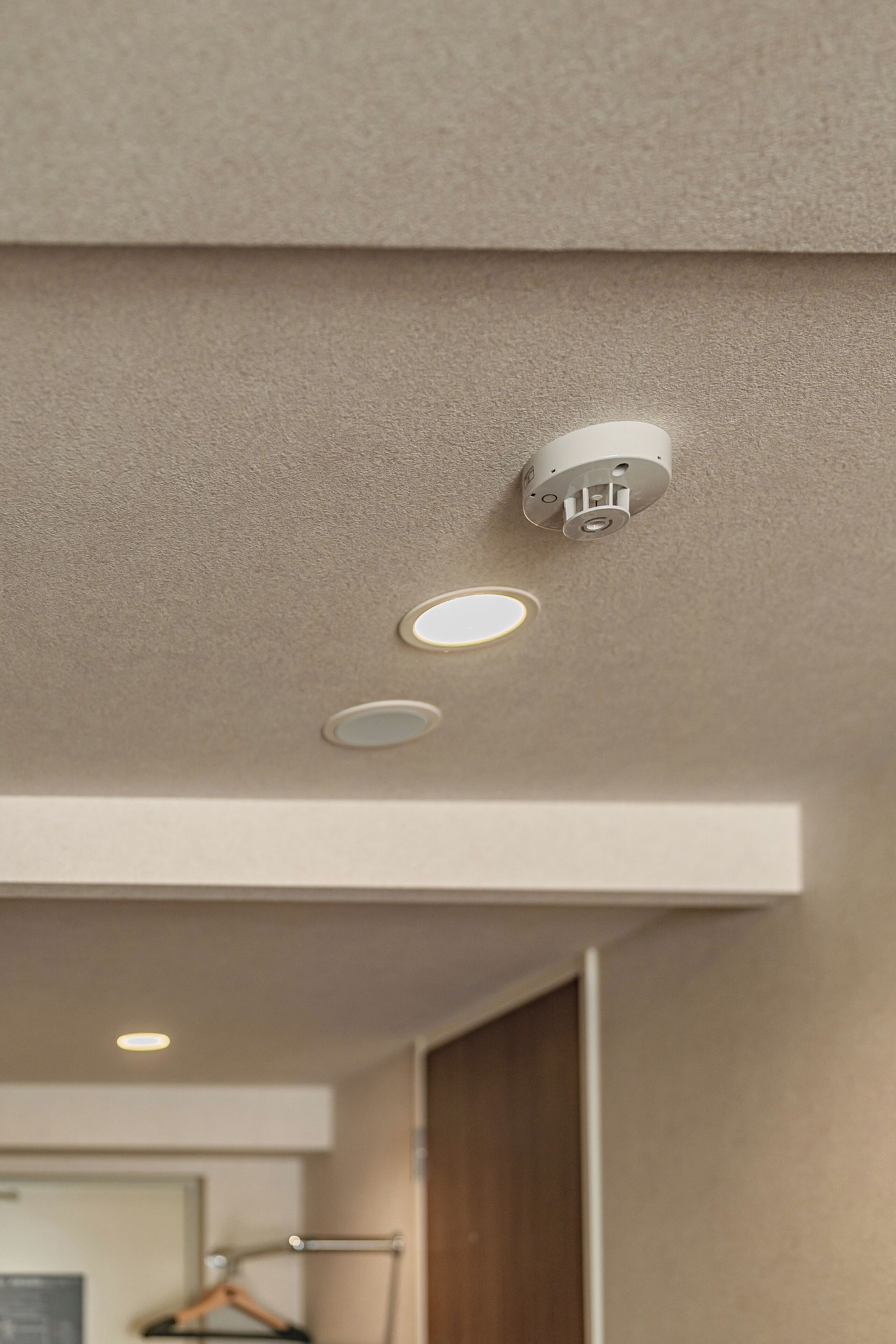 A ceiling with recessed lighting and a smoke detector.