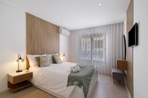 Une chambre moderne avec un lit, des tables de chevet, une télévision et une fenêtre avec des rideaux.