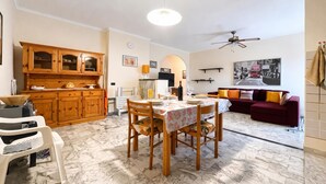Un comedor con una mesa dispuesta para dos personas, un aparador de madera y una cocina al fondo.