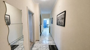 Un pasillo con suelo de mármol, cuadros en las paredes y una puerta que da a otra habitación.