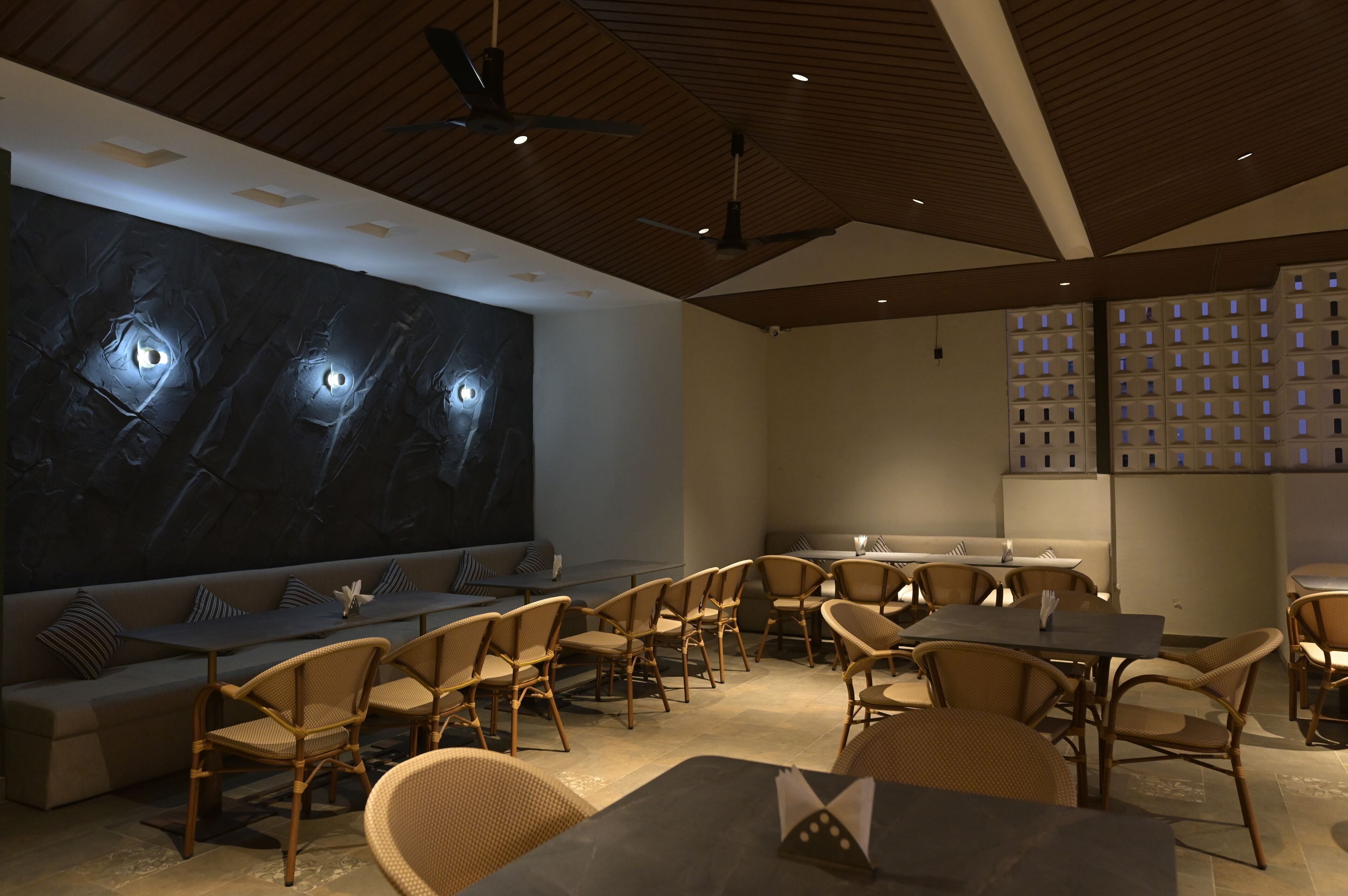 Un restaurant moderne doté d’une grande fresque murale, d’un plafond en bois et de sièges confortables.