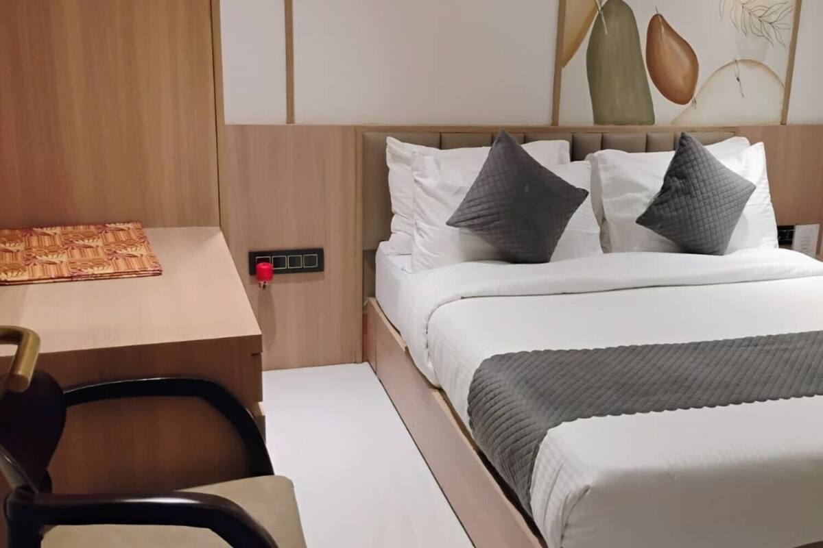 A neatly arranged bedroom with a bed, pillows, a bedside table, and a chair.