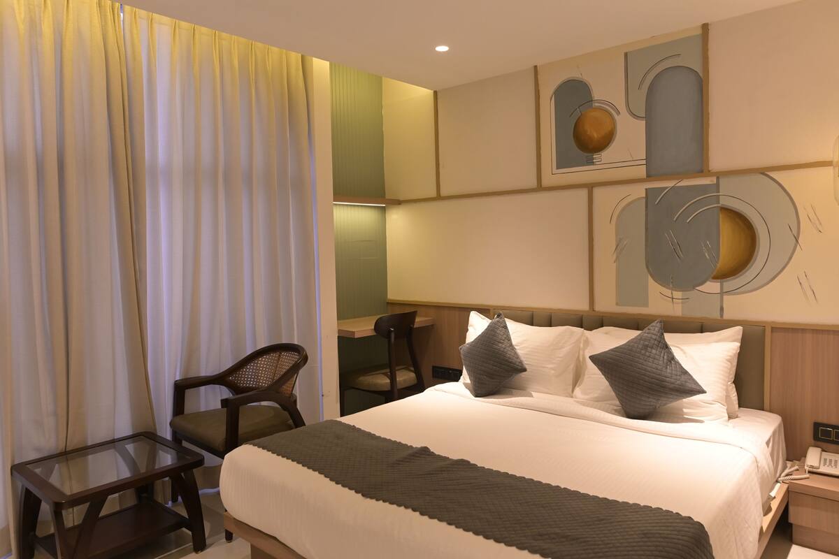 A hotel room with a bed, a desk, a chair, and a small table.