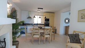 A modern kitchen with a dining area, featuring a central island, wooden chairs, and pendant lighting. - Residencia la Fuente (Mijas)