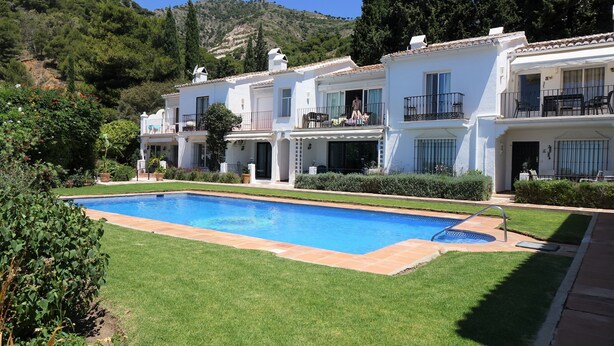 A two-story white building with a swimming pool, balconies, and a mountainous backdrop. - Residencia la Fuente (Mijas)