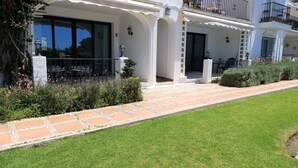 A two-story building with a white facade, large windows, and a paved walkway leading to a covered outdoor seating area. - Residencia la Fuente (Mijas)