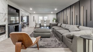 A modern living room with a grey sofa, wooden chair, and a TV.