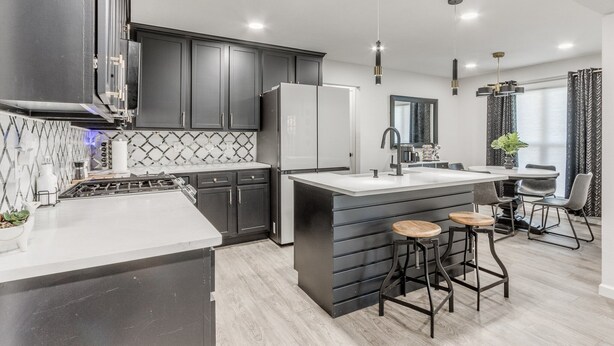 A modern kitchen with dark cabinets, a white countertop, and a central island with stools.