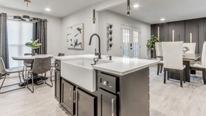 A modern kitchen with a central island, dark cabinetry, and pendant lighting.