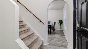 Eine Holzhandrail führt zu einem Essbereich mit Tisch und Stühlen, daneben ein Blumentopf.