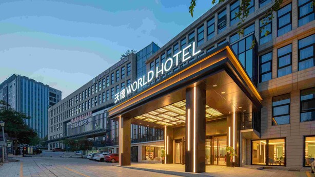 Een modern hotel met een opvallende entree, grote ramen en een goed verlichte gevel.