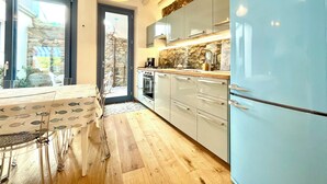 A modern kitchen with a blue refrigerator, wooden cabinets, and a stone backsplash.