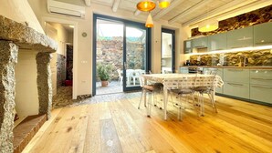 A modern kitchen with a stone wall, wooden flooring, and a dining area with a table and chairs.