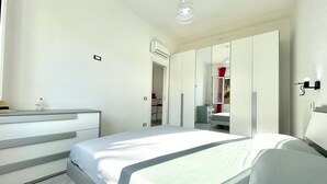 A modern bedroom with a bed, a dresser, a mirror, and a wardrobe.