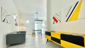 A modern living room with a sofa, a dining table, and a yellow and black console.