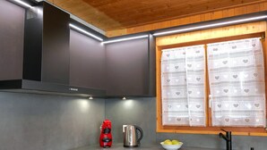 Uma cozinha moderna com coifa preta, eletrodomésticos de aço inoxidável e teto de madeira.