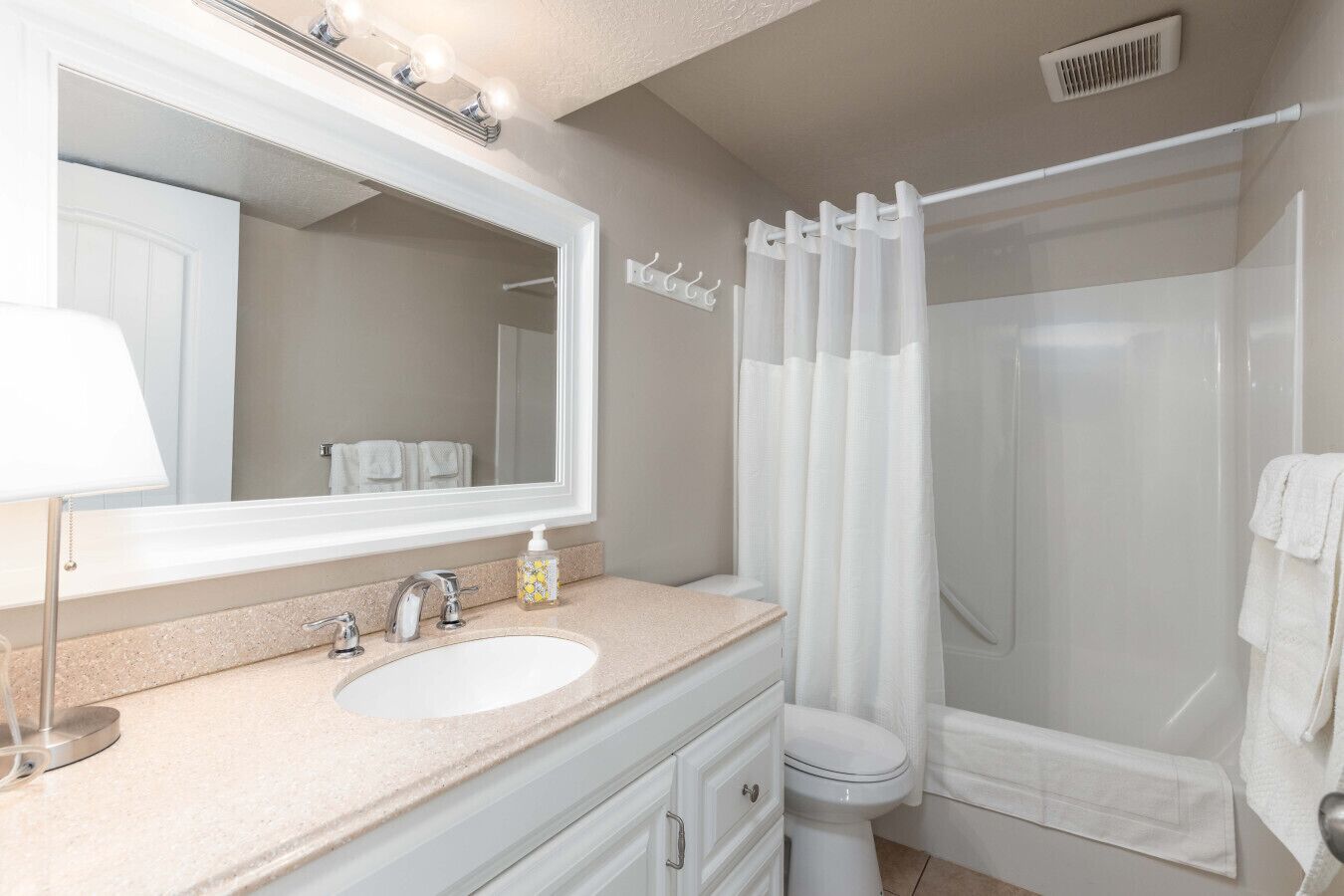 Une salle de bain équipée d’un lavabo, d’un miroir, de toilettes et d’un rideau de douche.