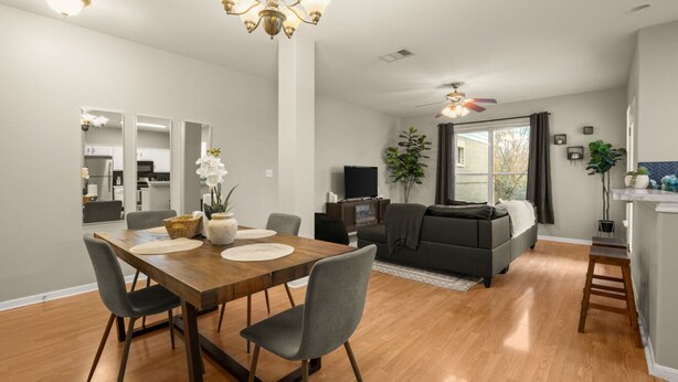 A modern living room with a dining area, a sofa, a TV, and a large window. - Cozy Retreat With Arcade Haven (Austin)
