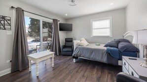 Une chambre à coucher moderne avec un lit, un bureau, une chaise et un téléviseur.